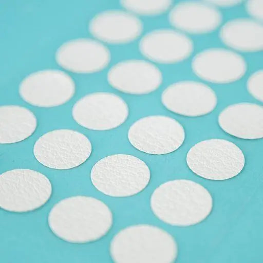 A sheet of Welsh white Dethleffs self-adhesive dot stickers on a transparent backing.