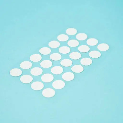 A sheet of Welsh white Dethleffs self-adhesive dot stickers on a transparent backing.