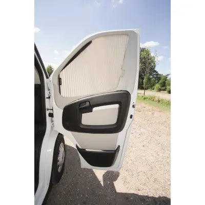 Motorhome door with a window blind, showing a clear sky and trees in the background.