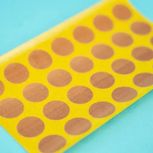 A sheet of topaz apfel / cypress villa Dethleffs self-adhesive dot stickers on a yellow backing.