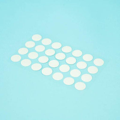 A sheet of Welsh white Dethleffs self-adhesive dot stickers on a transparent backing.