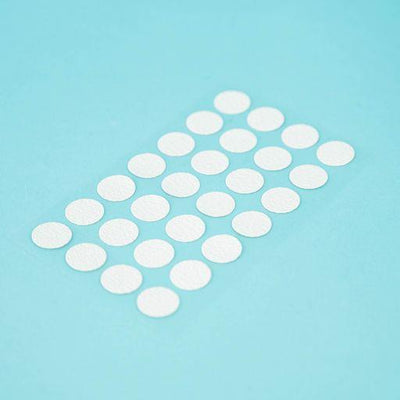 A sheet of Welsh white Dethleffs self-adhesive dot stickers on a transparent backing.
